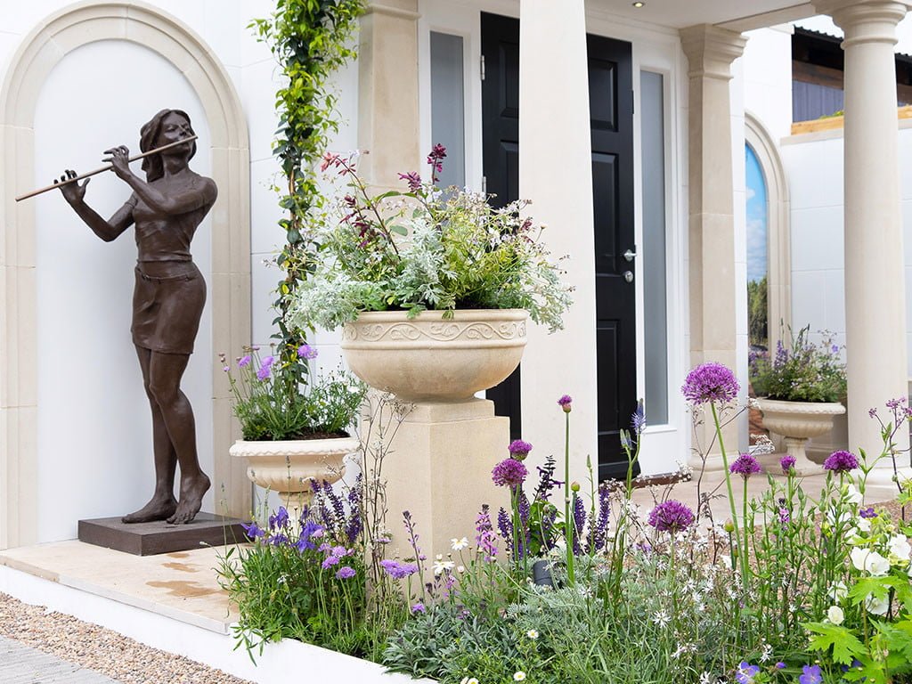 Chelsea show garden featuring cast stone garden ornaments, portico and bronze resin sculpture of woman playing the flute
