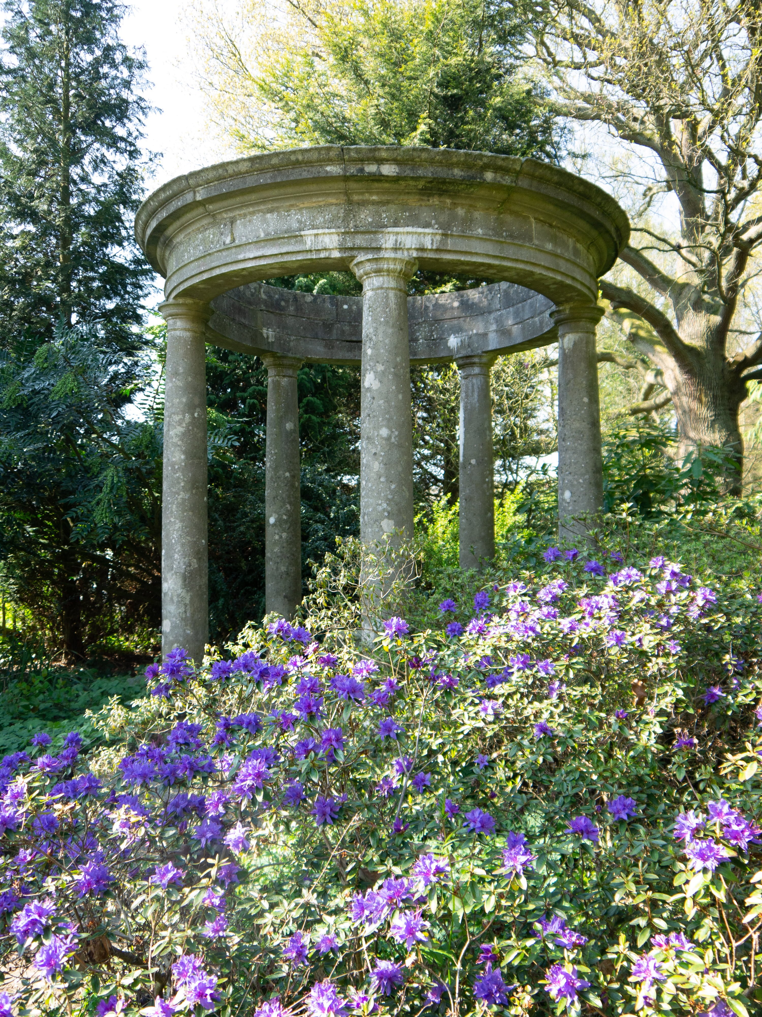 Aged Handmade Cast Stone Temple surrounded by purple flowers and trees
