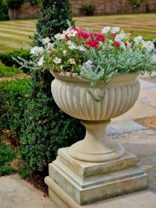 Small stone garden urn with an elegant neck, adorning a garden patio to create a new space for planting.