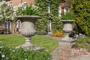 A pair of matching Chilstone urns create an inviting garden entrance.