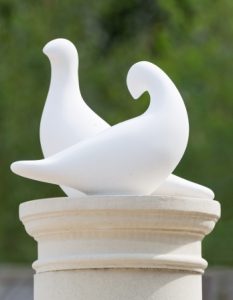 modern dove sculptures on stone pedestal with green background