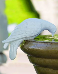 white stone dove statue drinking from stone birdbath