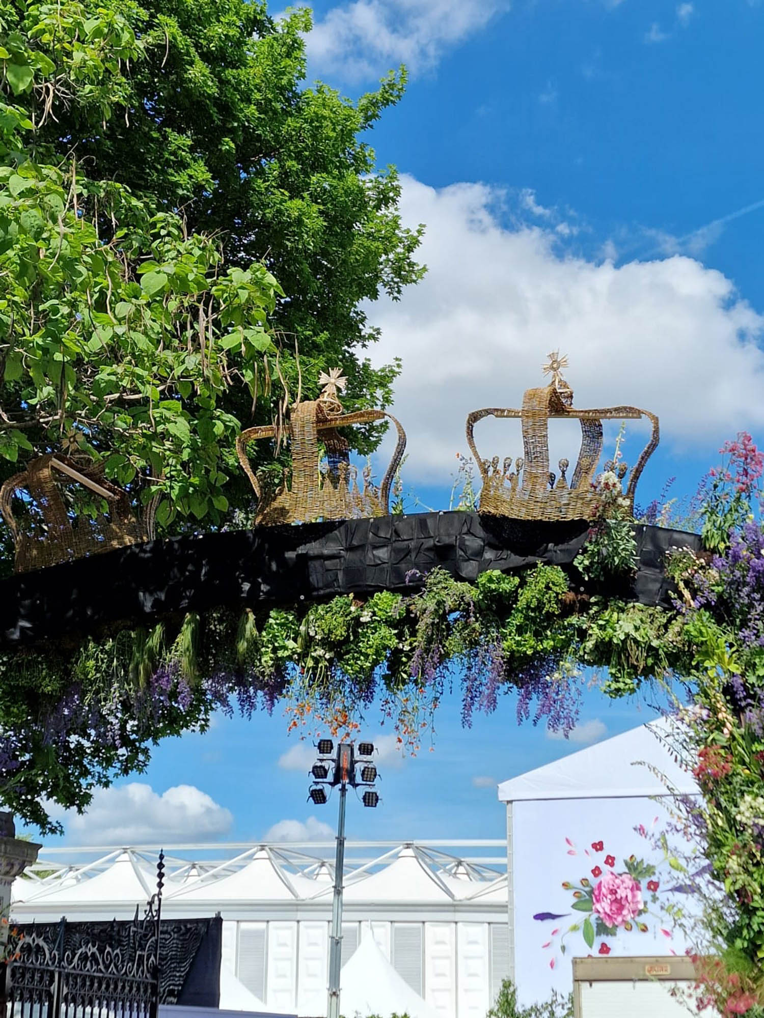 Queens gate at chelsea flower show 2022 is huge living floral arch with foliage and flowers and wicker crowns decorating the top as part of the jubilee celebrations in the gardens