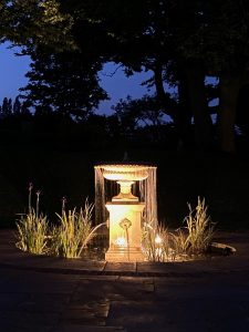 Classical fountain in a pond, beautifully lit at nighttime. Handcrafted by Chilstone.