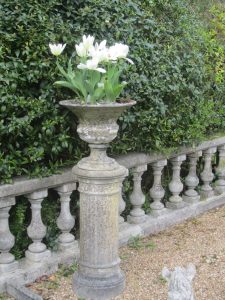 A small stone urn on a round pedestal within a balustraded patio.